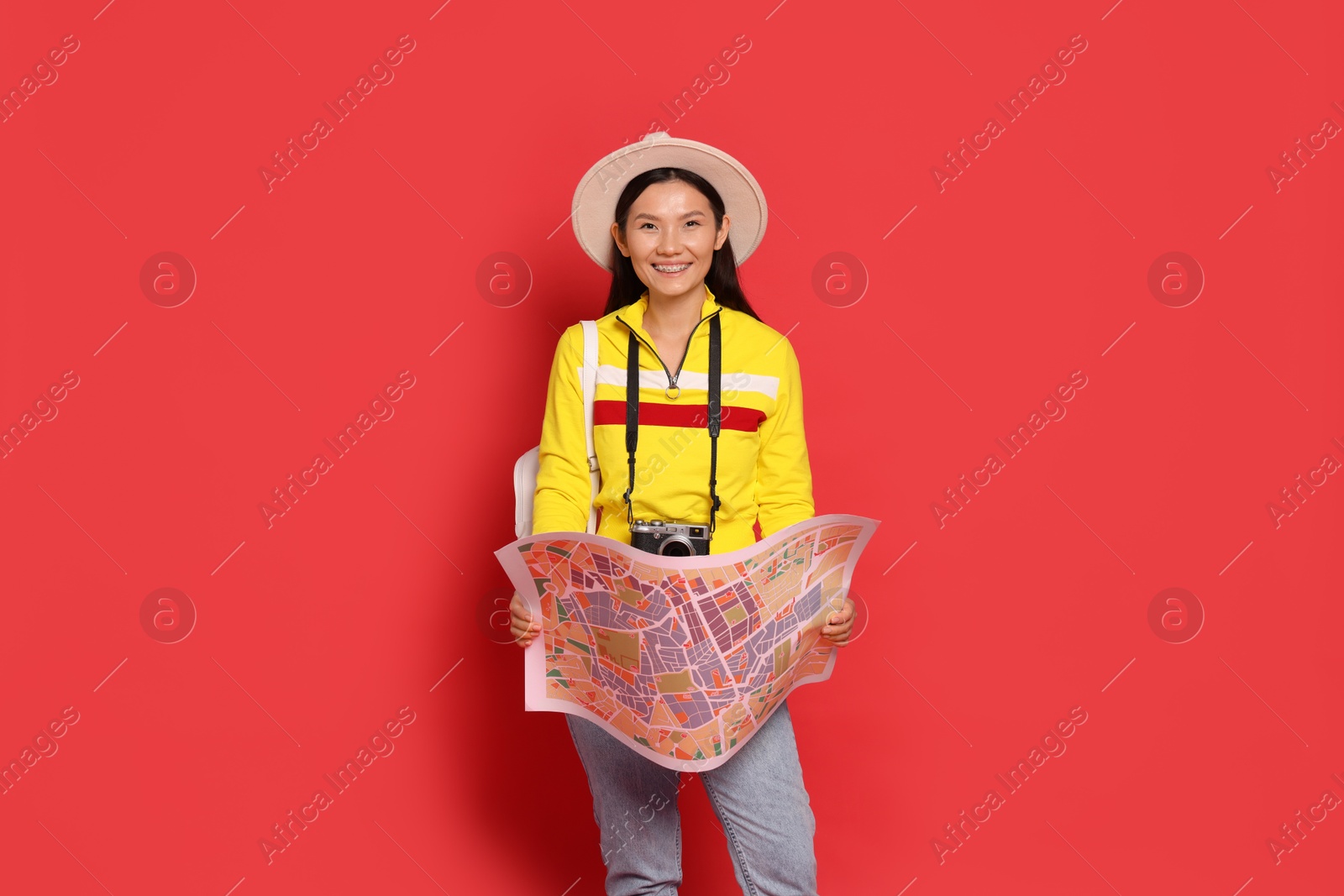 Photo of Happy traveller with map on red background