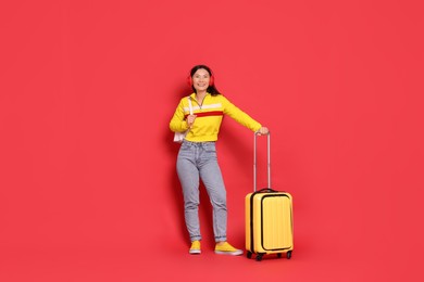 Photo of Happy traveller with suitcase on red background