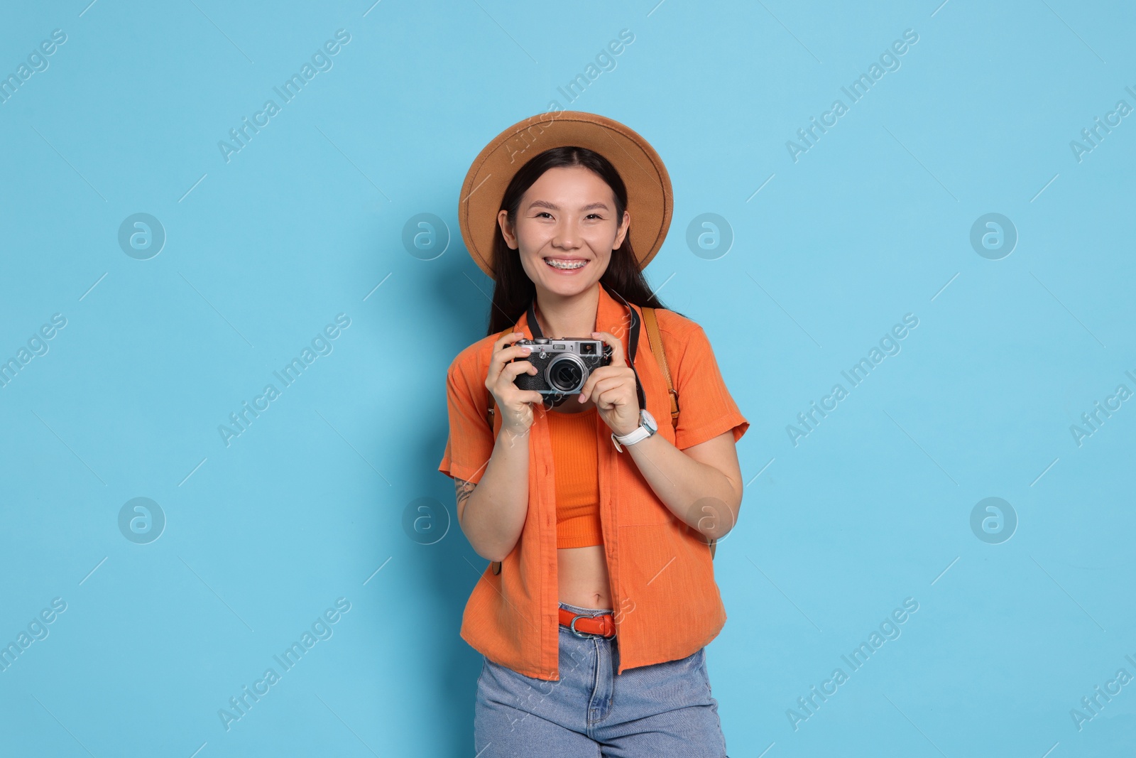 Photo of Happy traveller with camera on light blue background