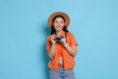 Photo of Happy traveller with camera on light blue background