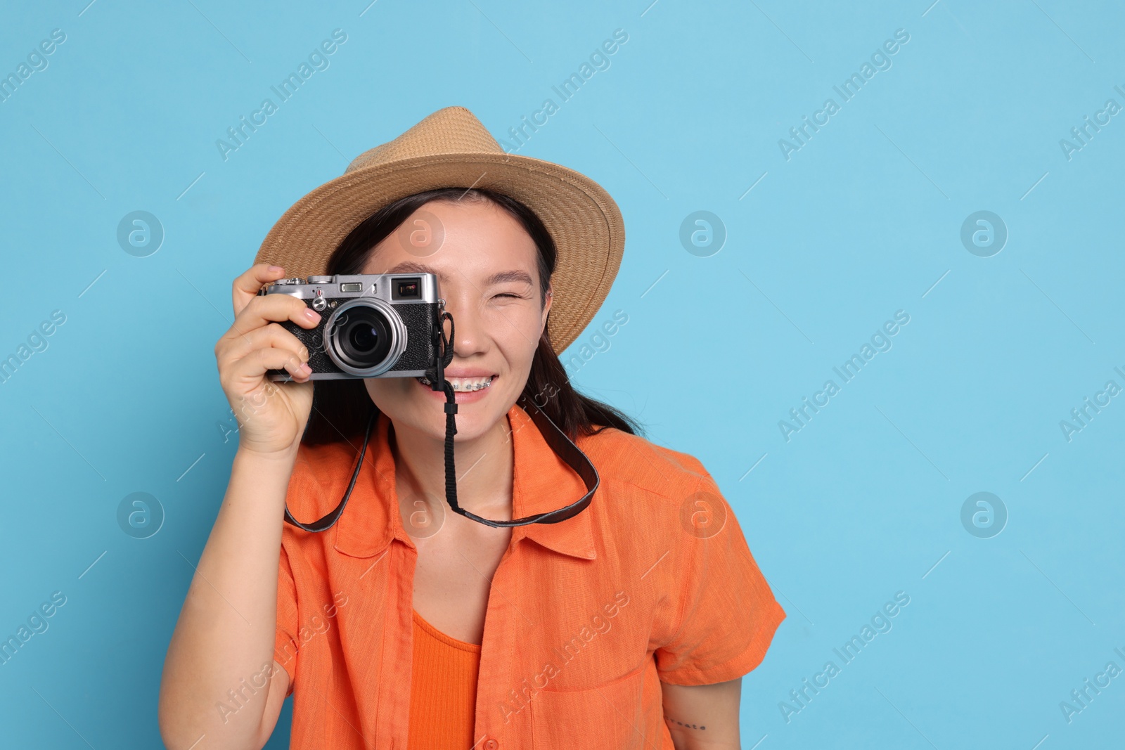 Photo of Happy traveller taking photo on light blue background. Space for text