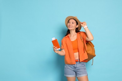 Photo of Happy traveller with backpack and passport on light blue background. Space for text