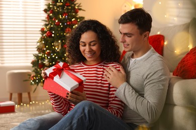 Photo of Happy couple with Christmas gift spending time together at home