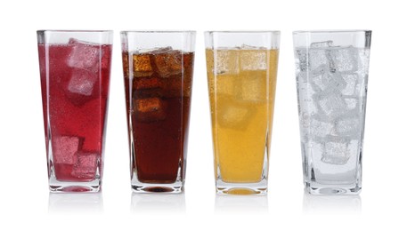 Photo of Soda water of different flavors with ice cubes in glasses isolated on white