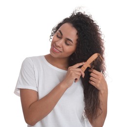 Photo of Smiling young woman brushing her curly hair with comb on white background