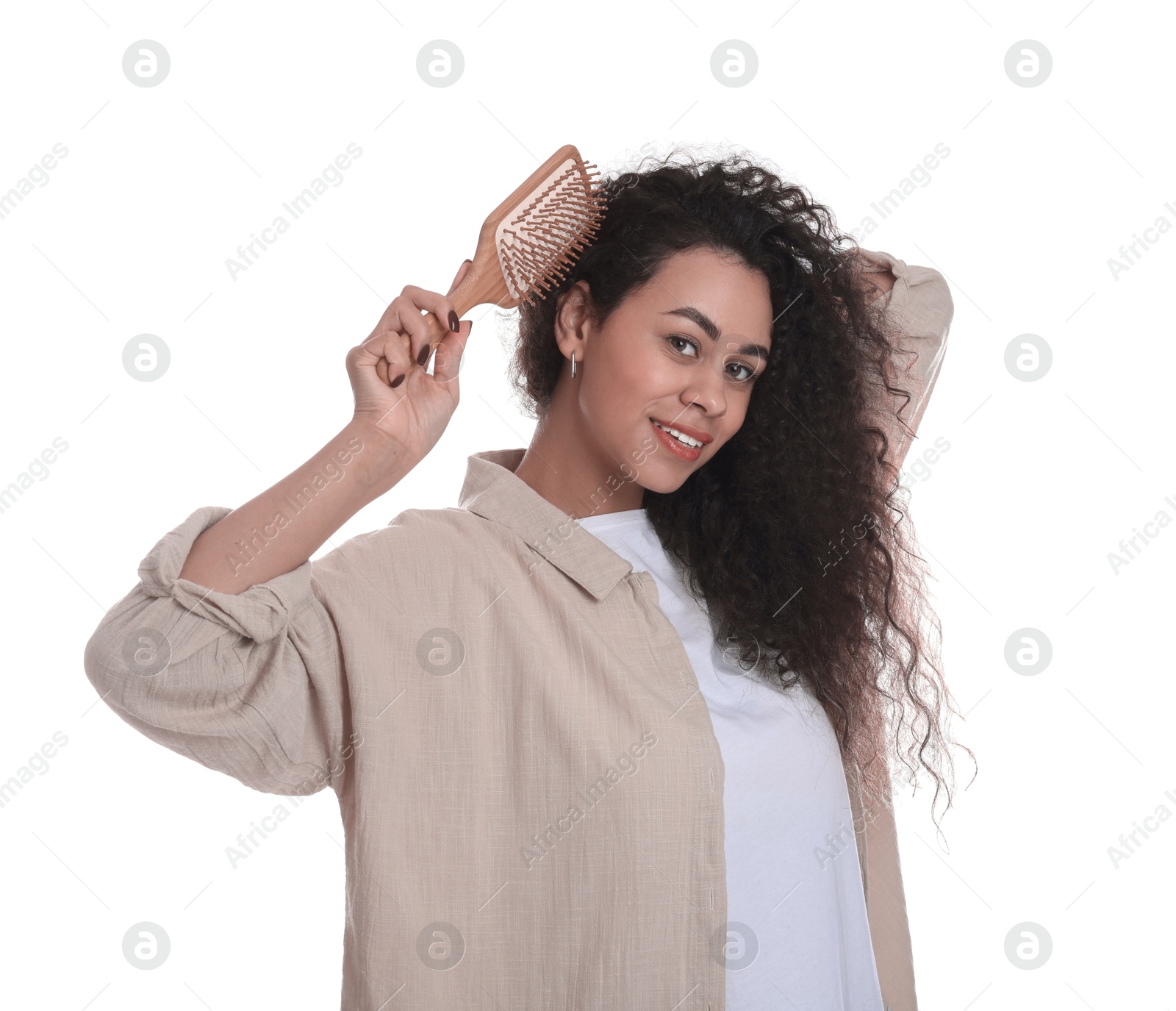 Photo of Smiling young woman brushing her curly hair on white background