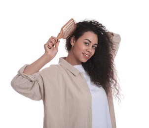 Photo of Smiling young woman brushing her curly hair on white background