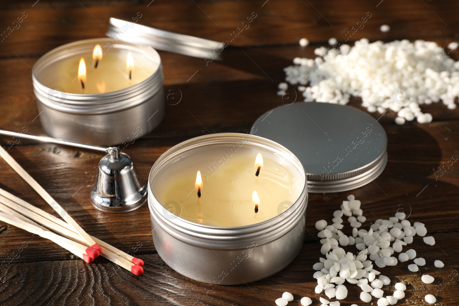 Photo of Burning soy wax candles, matches and snuffer on wooden table, closeup