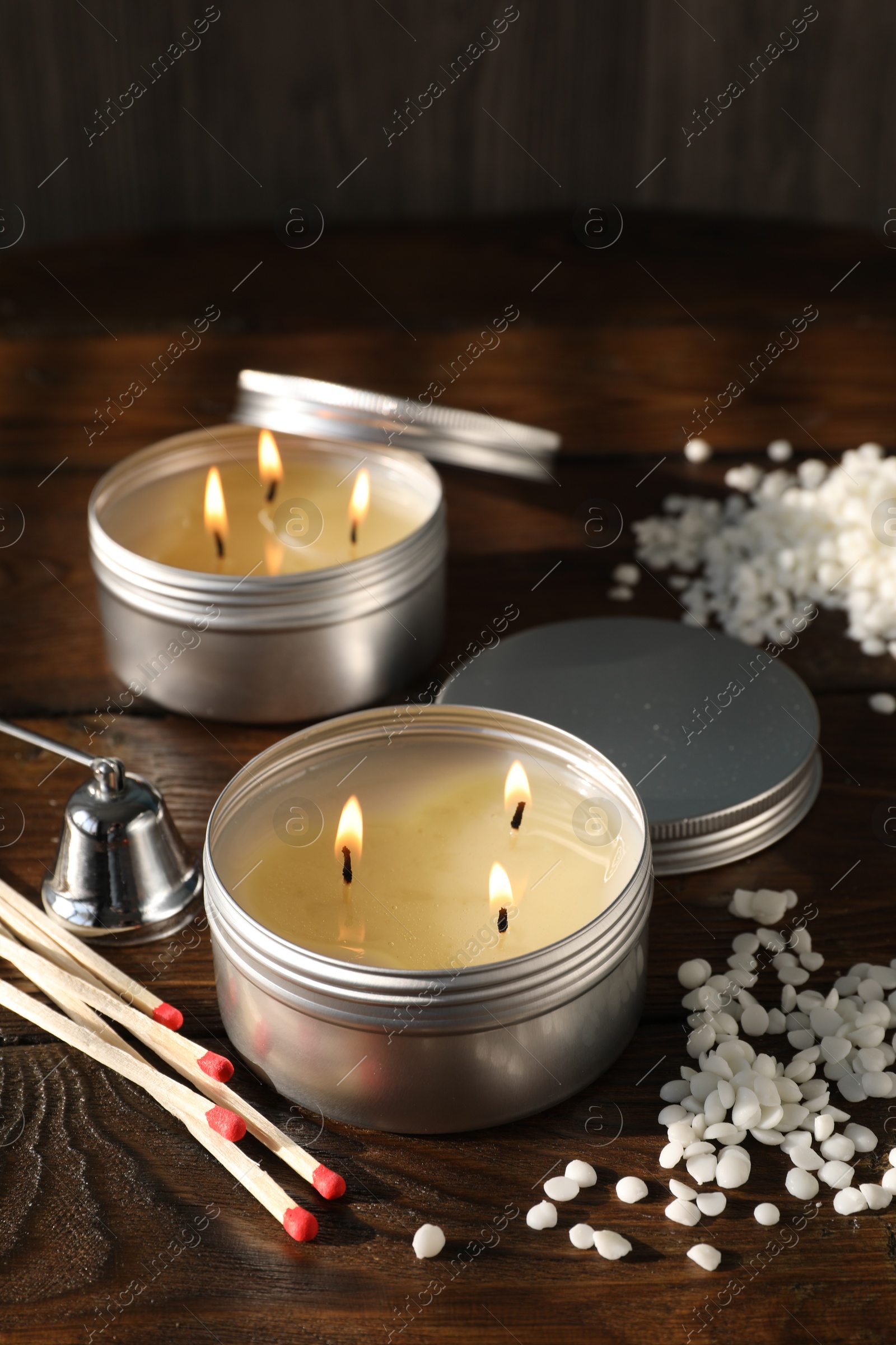 Photo of Burning soy wax candles, matches and snuffer on wooden table, closeup