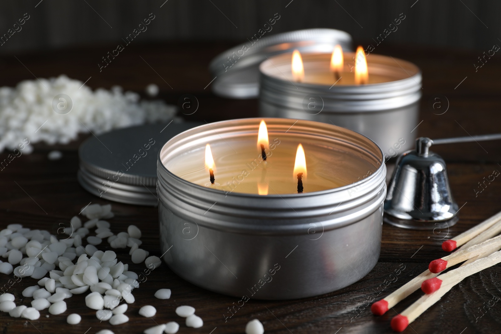 Photo of Burning soy wax candles, matches and snuffer on wooden table, closeup