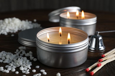 Photo of Burning soy wax candles, matches and snuffer on wooden table, closeup