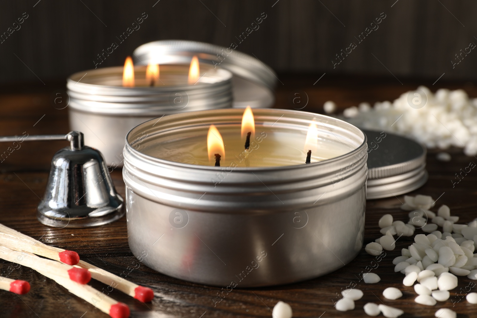 Photo of Burning soy wax candles, matches and snuffer on wooden table, closeup