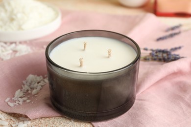 Photo of Soy wax candle and pink napkin on table, closeup