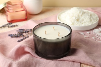 Photo of Soy wax candle, pink napkin and lavender flowers on table