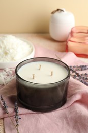 Photo of Soy wax candle, pink napkin and lavender flowers on table against beige background