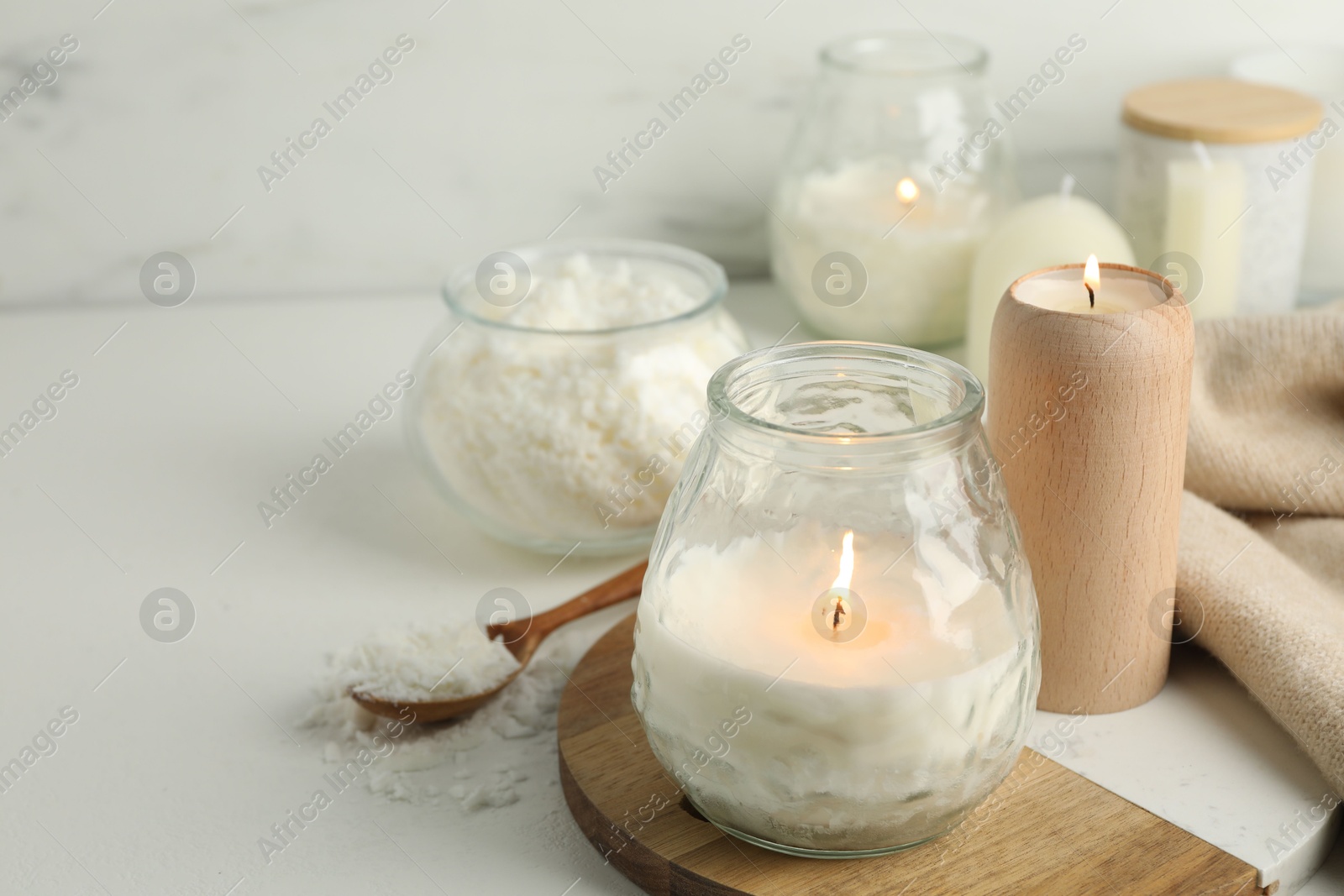 Photo of Burning soy wax candles on light table, closeup. Space for text