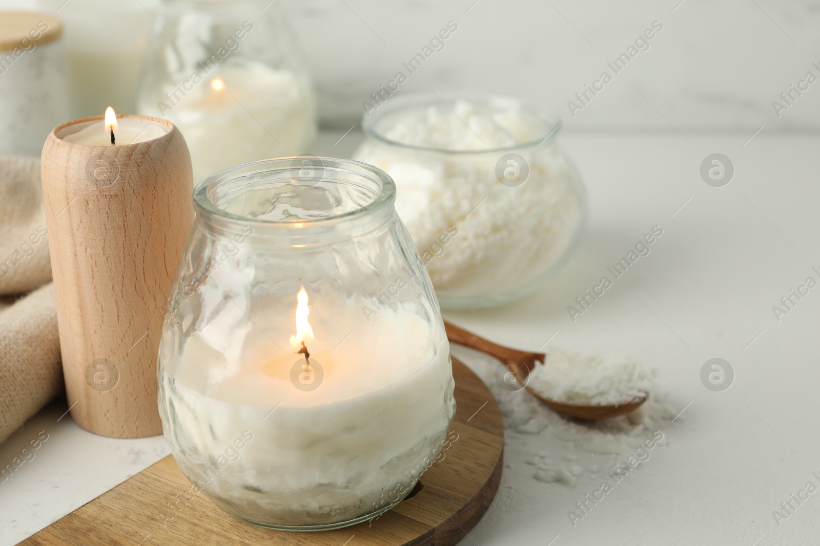 Photo of Burning soy wax candles on light table, closeup. Space for text