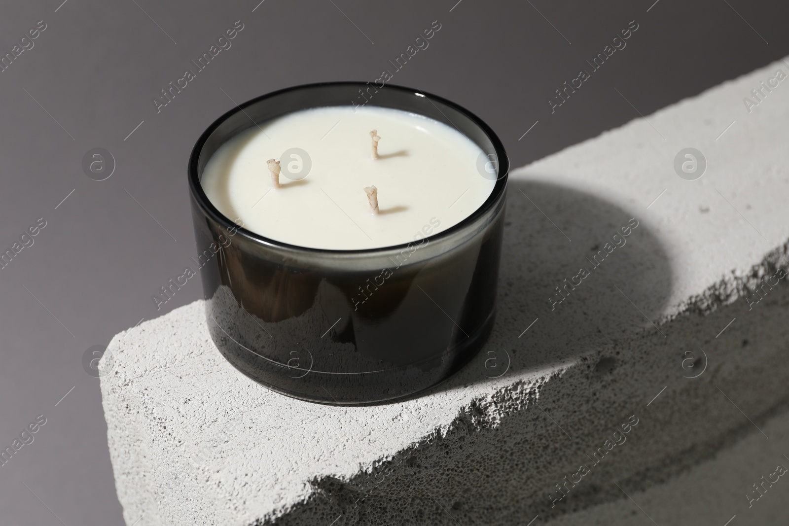 Photo of Soy wax candle on concrete block against gray background