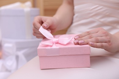 Photo of Bride opening beautiful wedding gift indoors, closeup