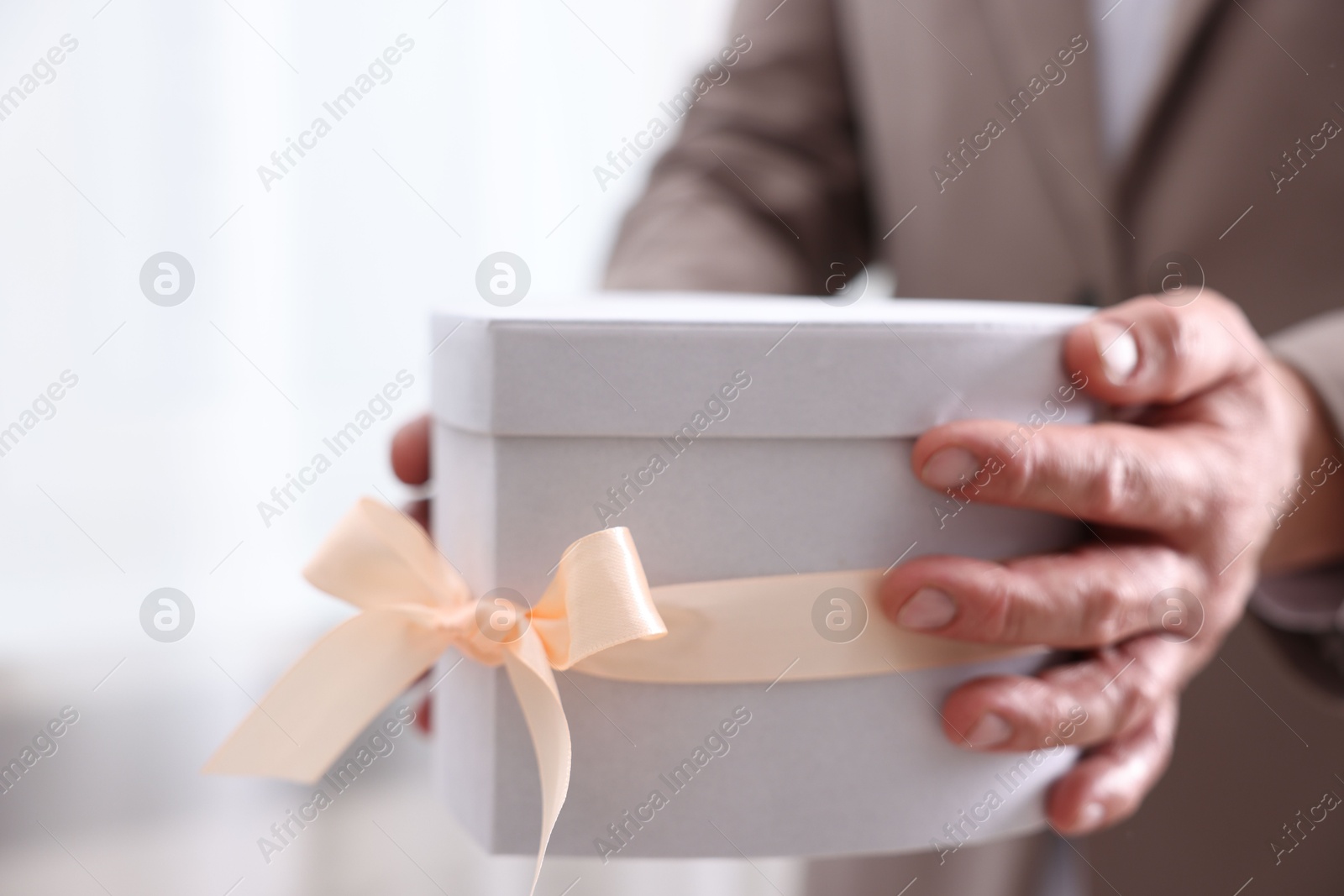 Photo of Groom with beautiful wedding gift indoors, closeup