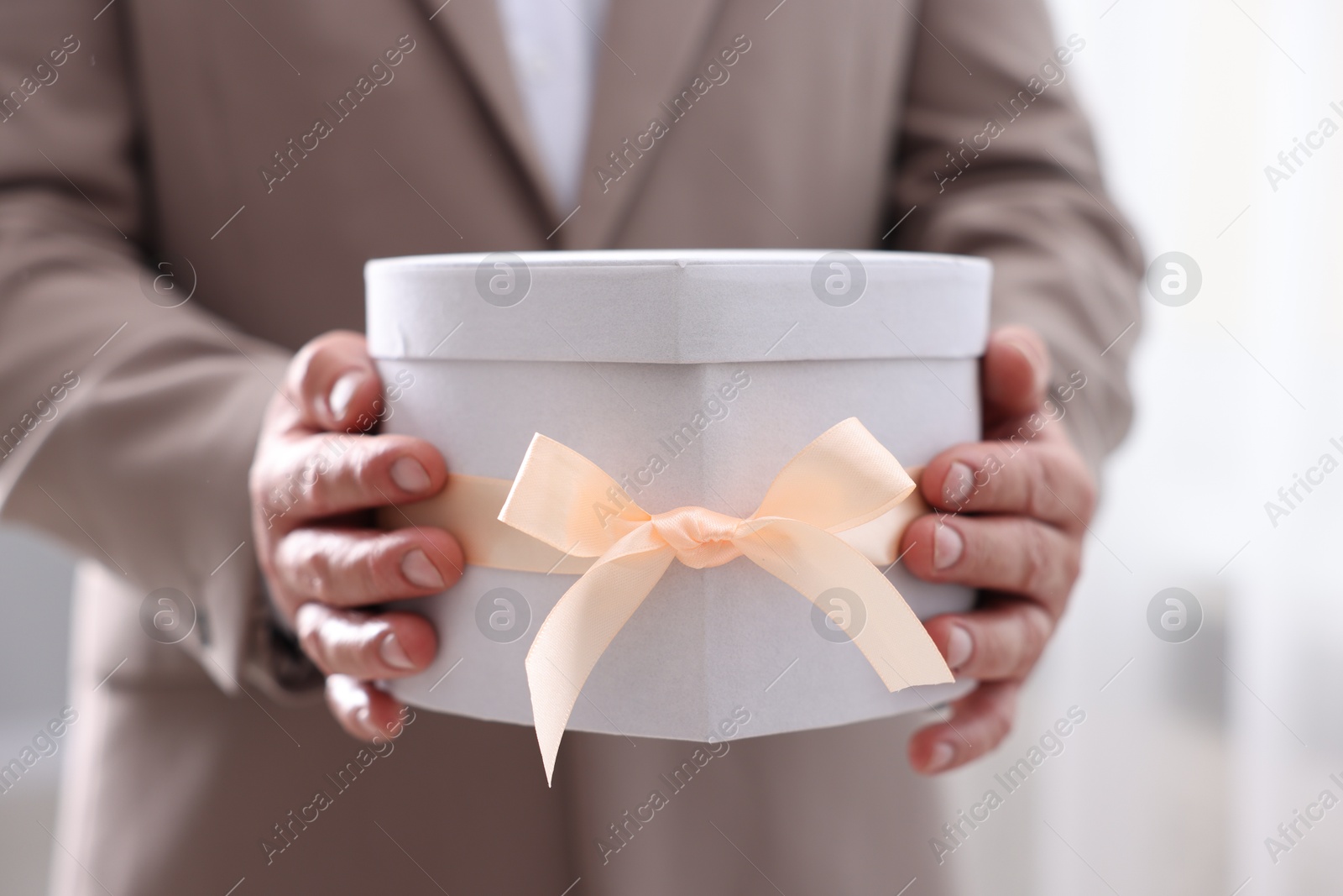 Photo of Groom with beautiful wedding gift indoors, closeup