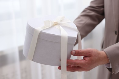 Photo of Groom with beautiful wedding gift indoors, closeup