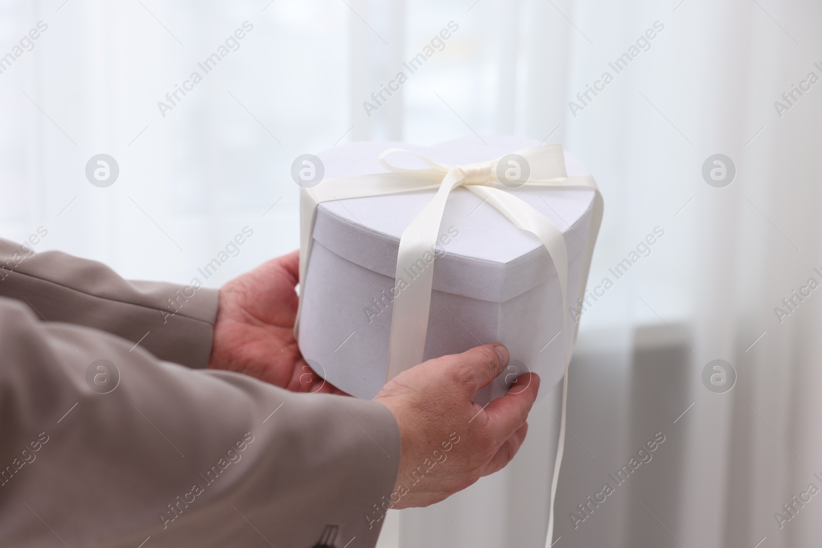 Photo of Groom with beautiful wedding gift indoors, closeup. Space for text