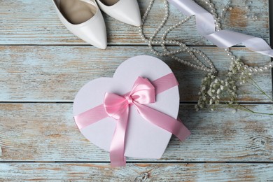 Photo of Beautiful wedding gift, pearl jewelry, ribbon, bridal shoes and gypsophila flowers on wooden table, flat lay. Space for text