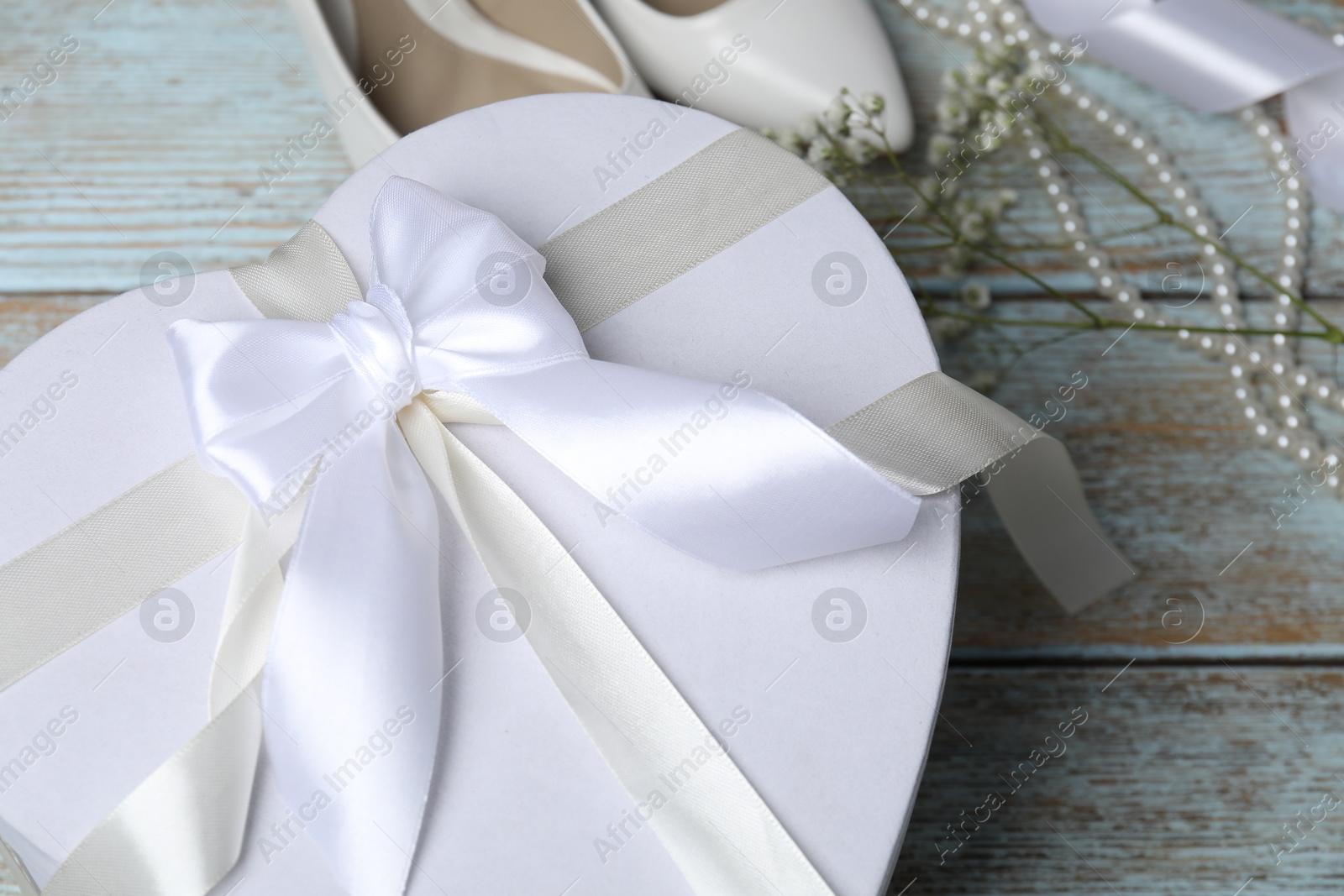 Photo of Beautiful wedding gift, pearl jewelry, bridal shoes and gypsophila flowers on wooden table, closeup