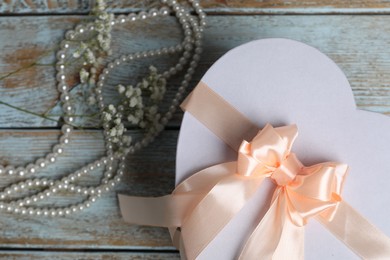 Photo of Beautiful wedding gift, pearl jewelry and gypsophila flowers on wooden table, flat lay