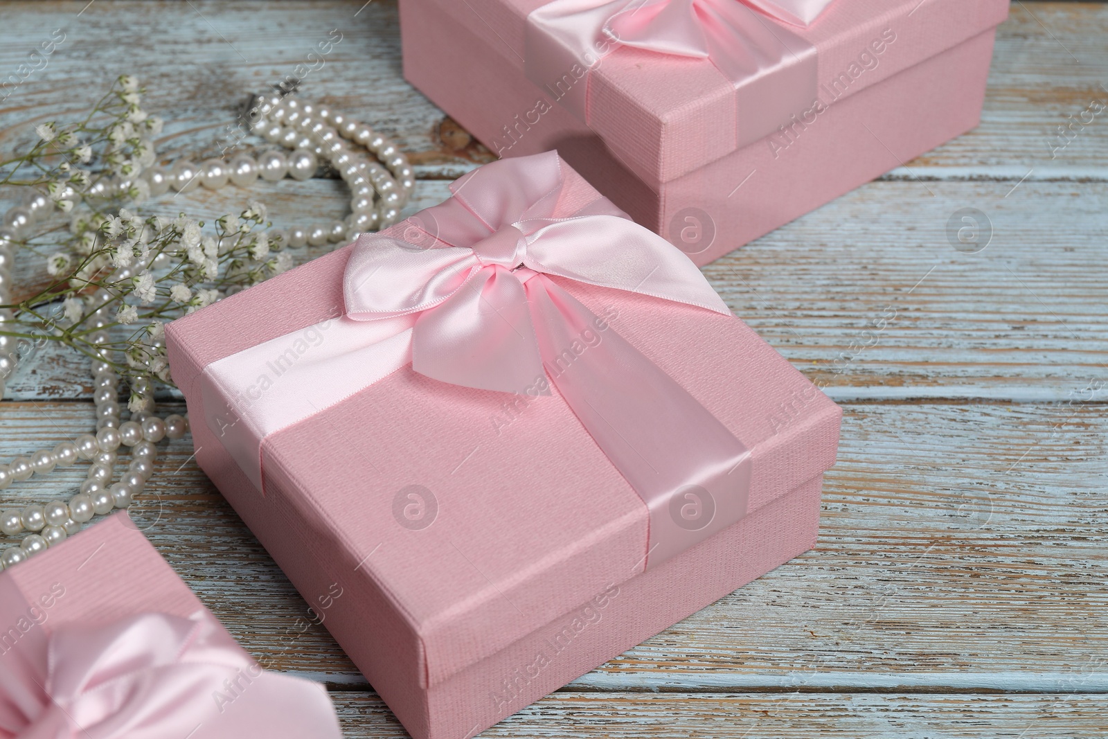 Photo of Beautiful wedding gifts, pearl jewelry and gypsophila flowers on wooden table, closeup