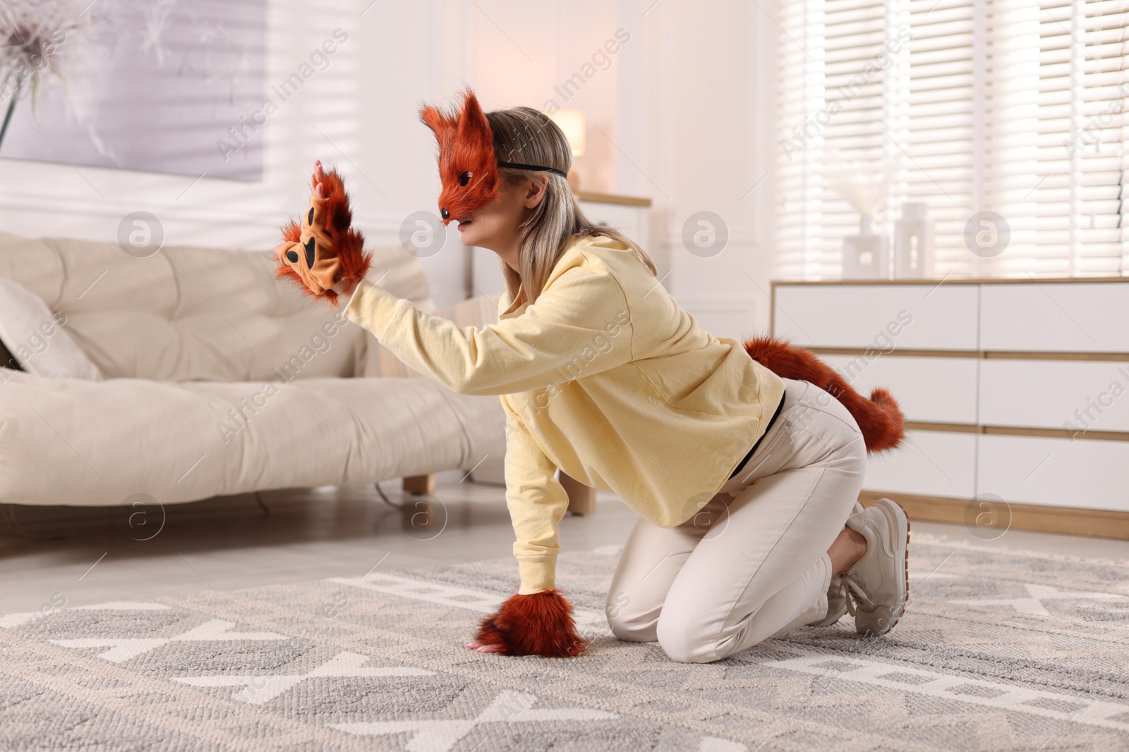 Photo of Quadrobics. Woman wearing fox mask, gloves and tail at home