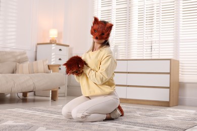 Photo of Quadrobics. Woman wearing fox mask and gloves at home