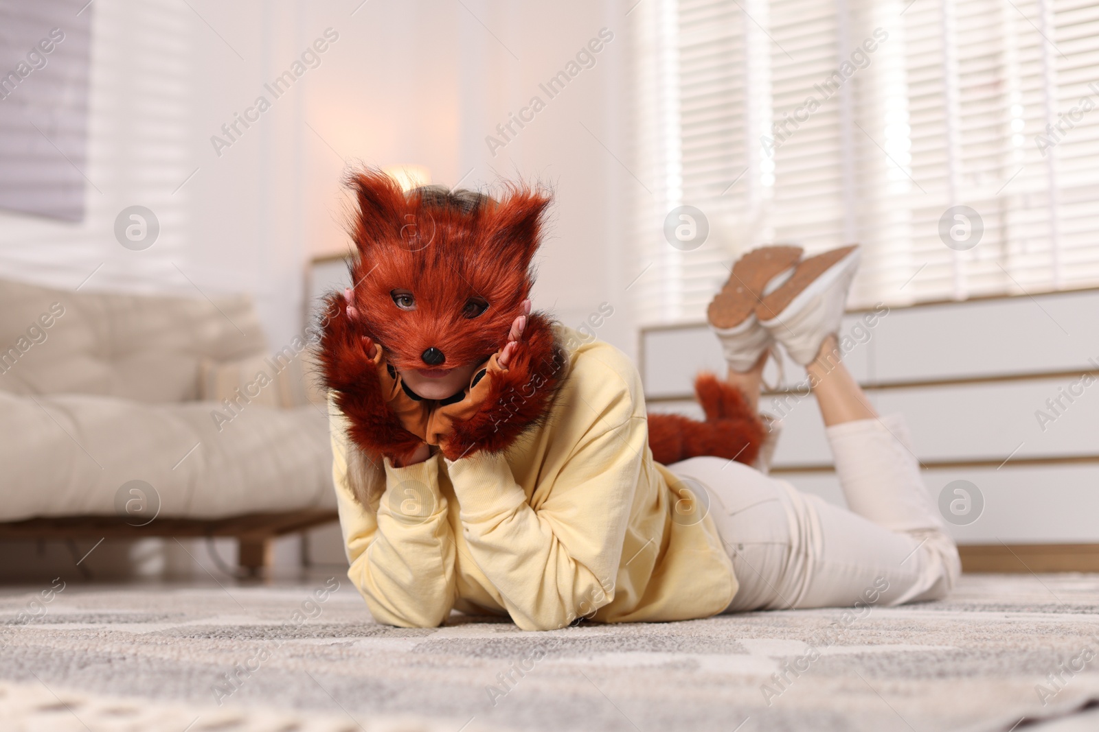 Photo of Quadrobics. Woman wearing fox mask, gloves and tail at home