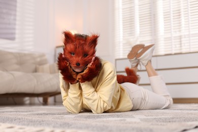 Photo of Quadrobics. Woman wearing fox mask, gloves and tail at home