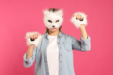 Photo of Quadrobics. Woman wearing cat mask and gloves on pink background