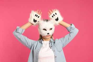 Photo of Quadrobics. Woman wearing cat mask and gloves on pink background