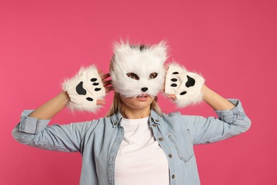 Photo of Quadrobics. Woman wearing cat mask and gloves on pink background