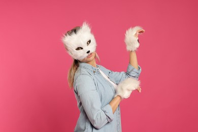 Photo of Quadrobics. Woman wearing cat mask and gloves on pink background