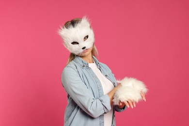 Photo of Quadrobics. Woman wearing cat mask and gloves on pink background