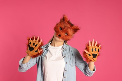 Photo of Quadrobics. Woman wearing fox mask and gloves on pink background