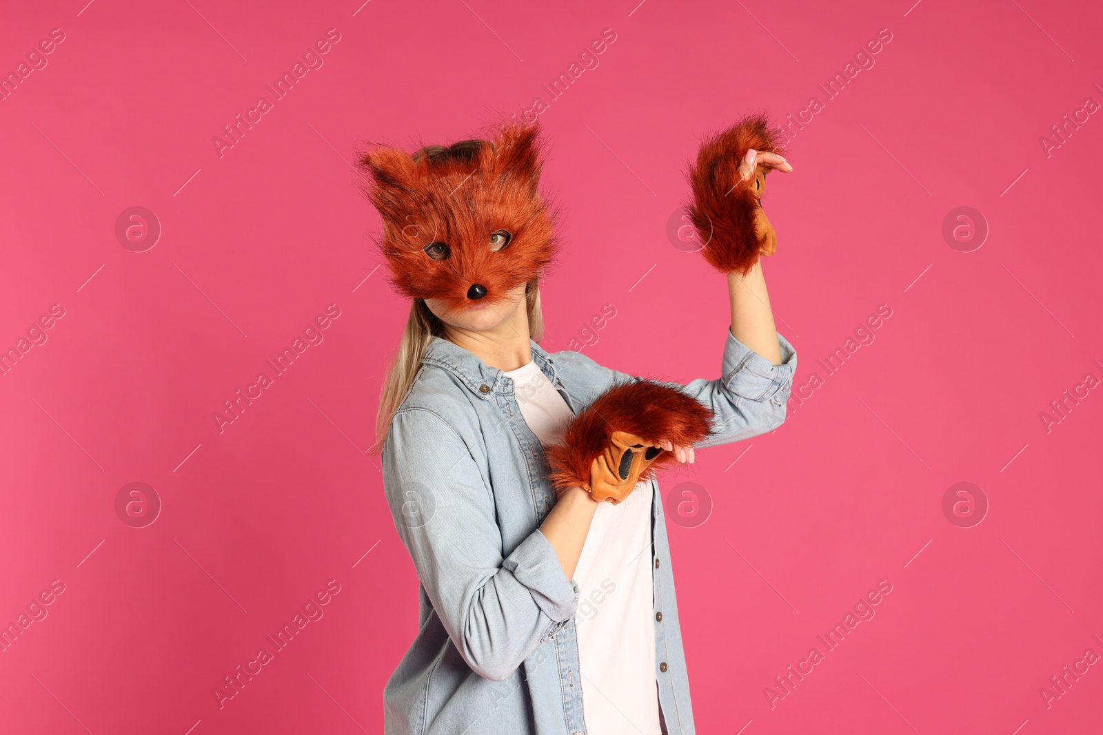 Photo of Quadrobics. Woman wearing fox mask and gloves on pink background