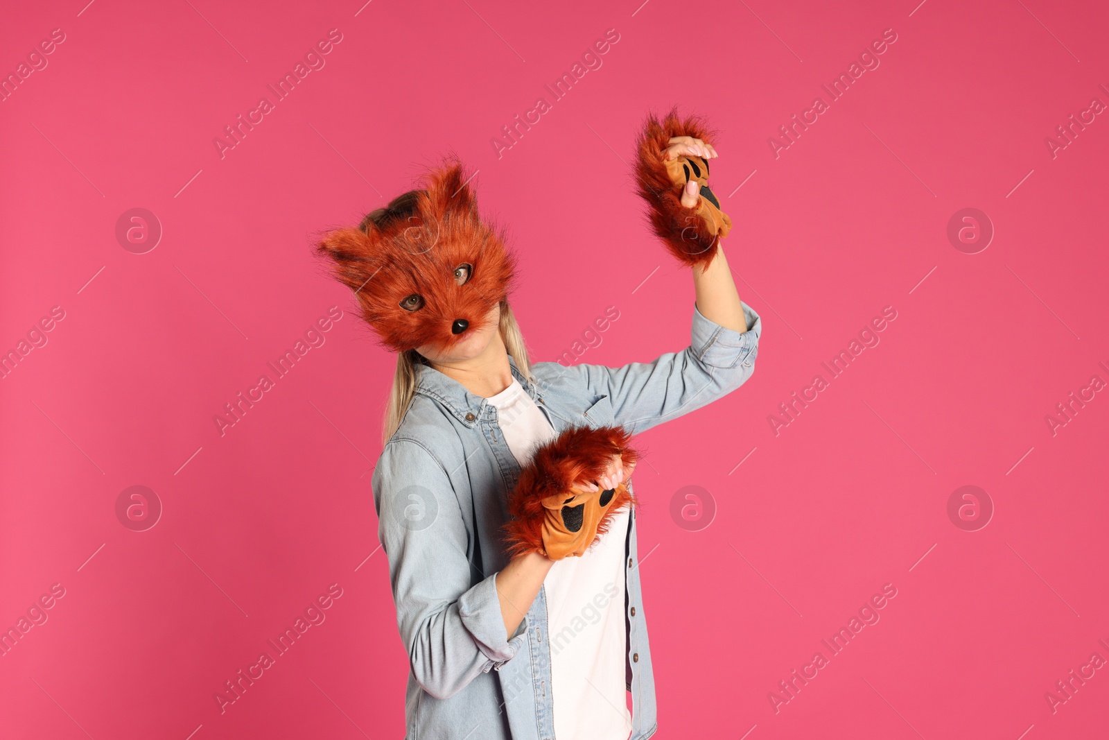 Photo of Quadrobics. Woman wearing fox mask and gloves on pink background