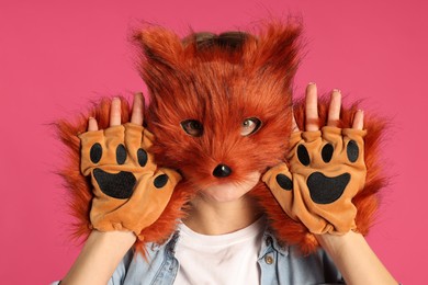 Photo of Quadrobics. Woman wearing fox mask and gloves on pink background