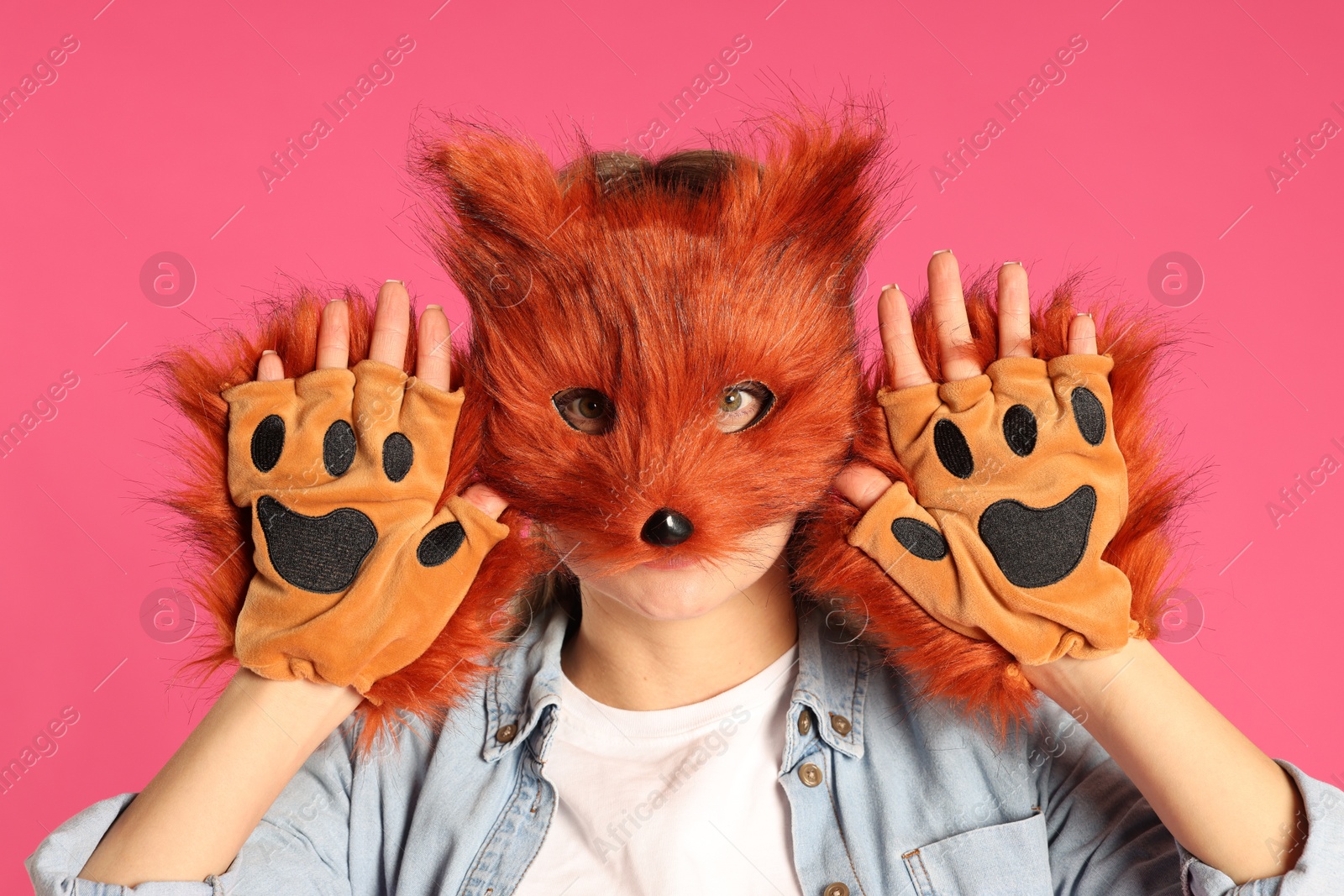 Photo of Quadrobics. Woman wearing fox mask and gloves on pink background