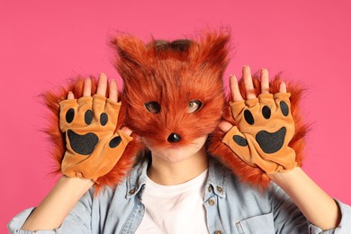 Photo of Quadrobics. Woman wearing fox mask and gloves on pink background