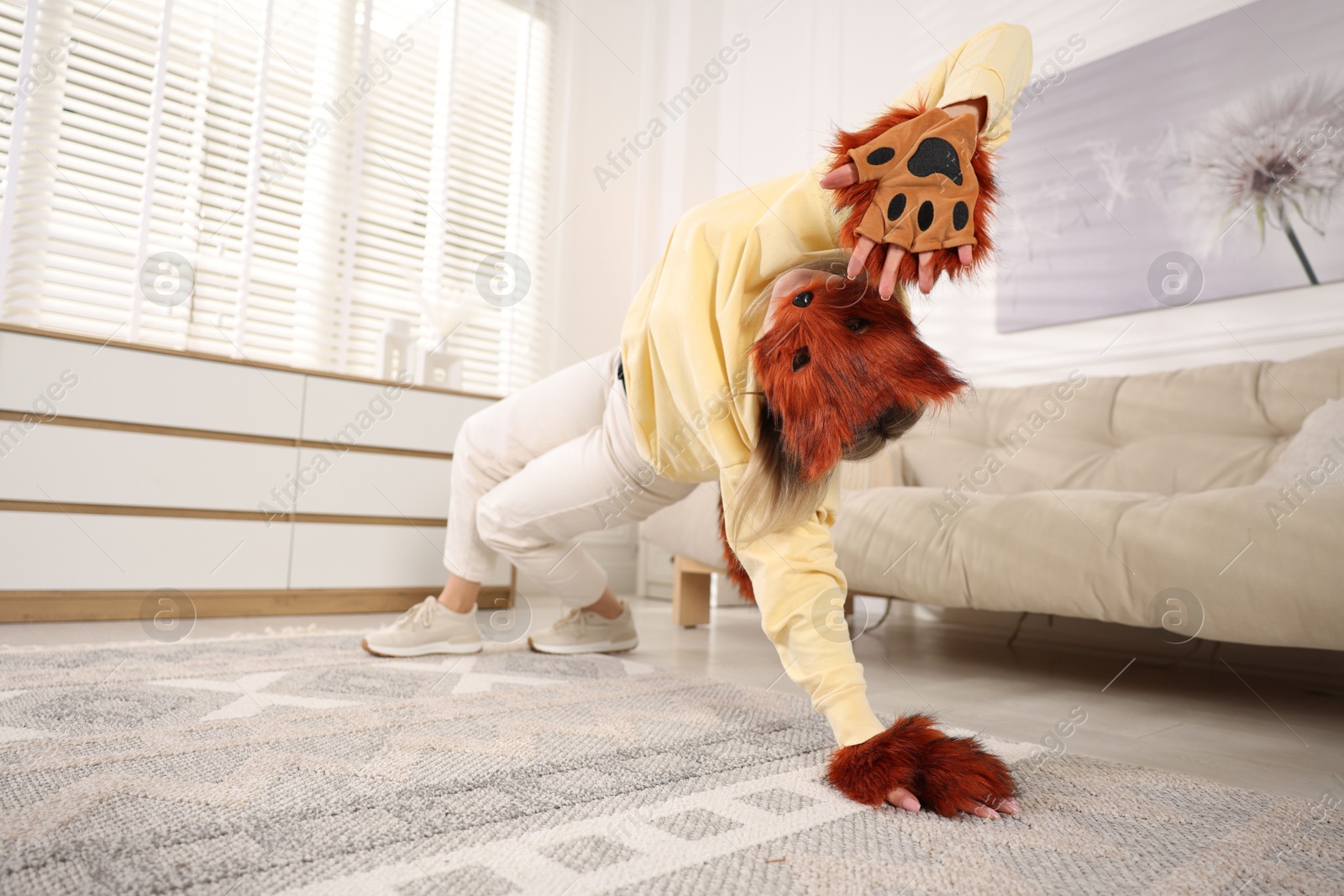 Photo of Quadrobics. Woman wearing fox mask and gloves at home