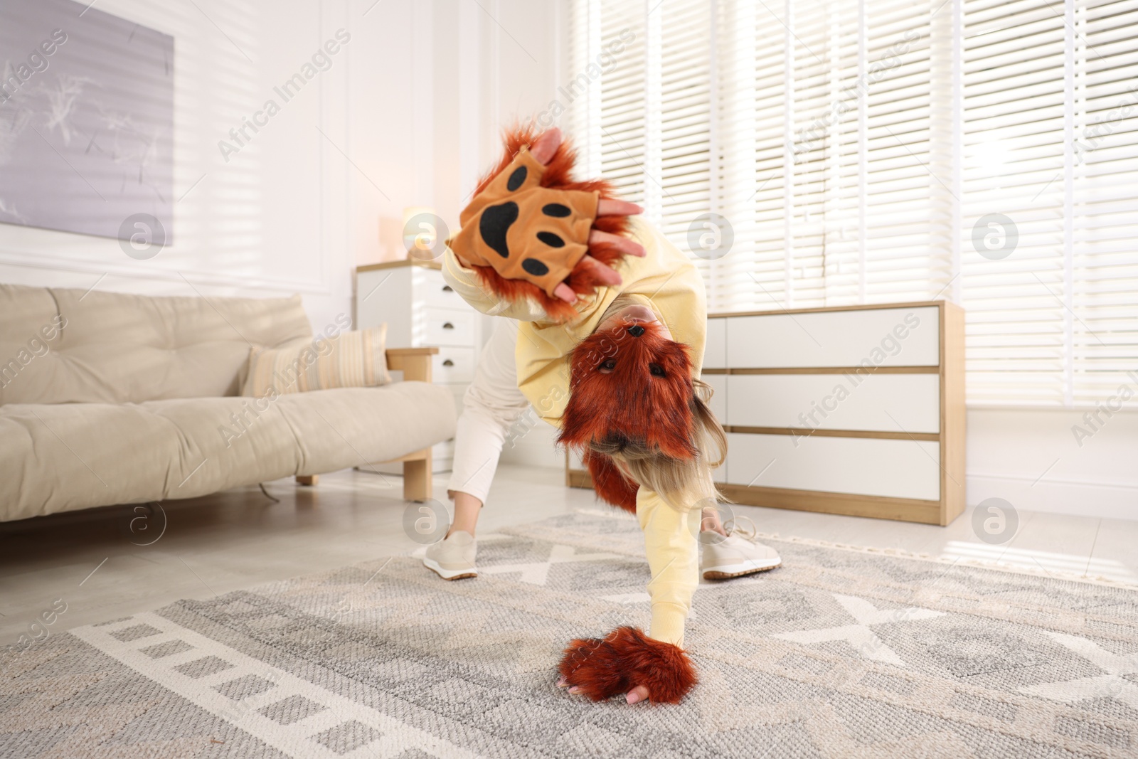 Photo of Quadrobics. Woman wearing fox mask, gloves and tail at home