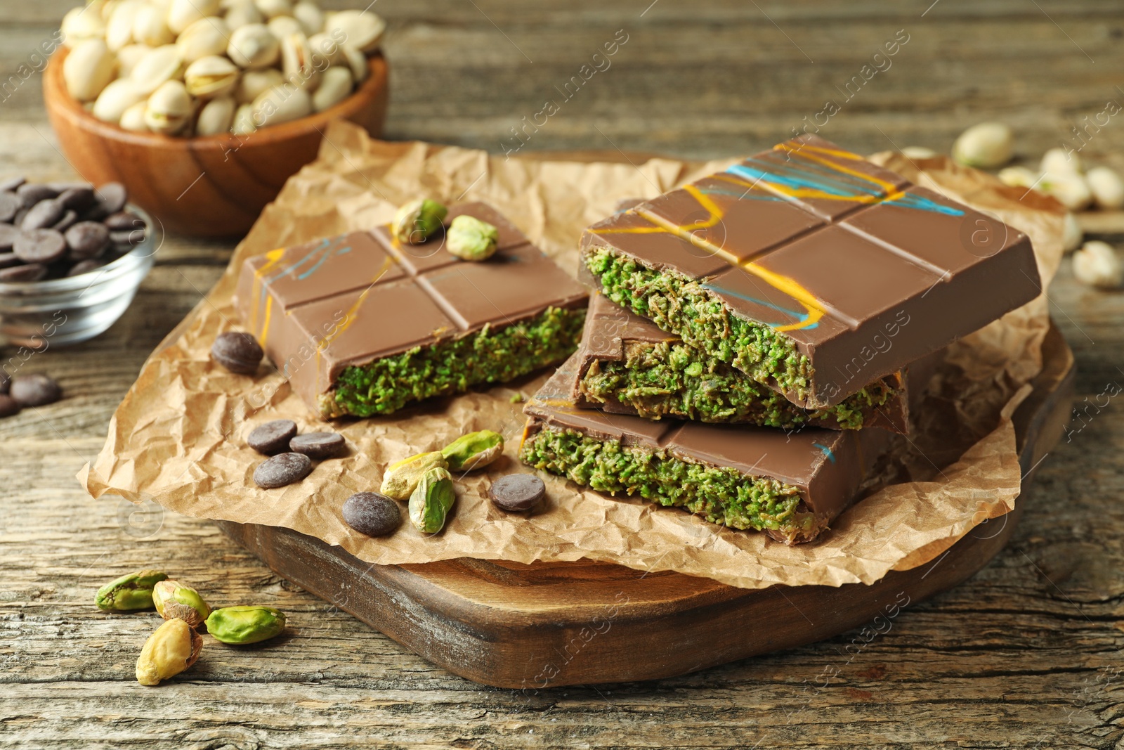 Photo of Pieces of Dubai chocolate bar with pistachios, knafeh and cacao chips on wooden table, closeup