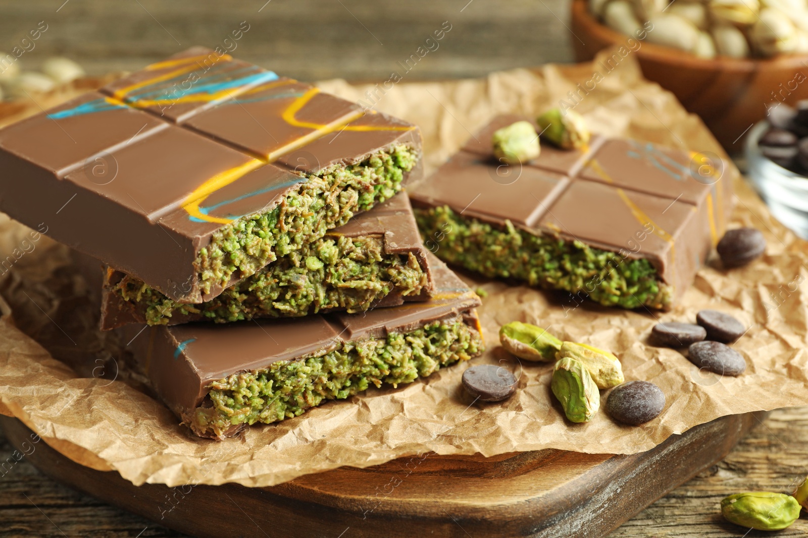 Photo of Pieces of Dubai chocolate bar with pistachios, knafeh and cacao chips on wooden table, closeup